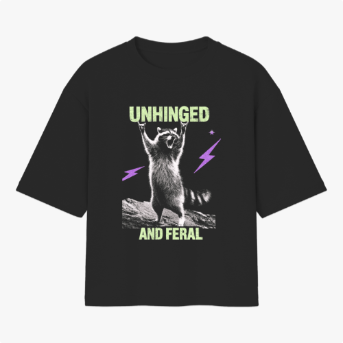 Camiseta com estampa frontal de guaxinim em pose dinâmica com raios ao redor, acompanhada das palavras "UNHINGED" acima e "AND FERAL" abaixo.