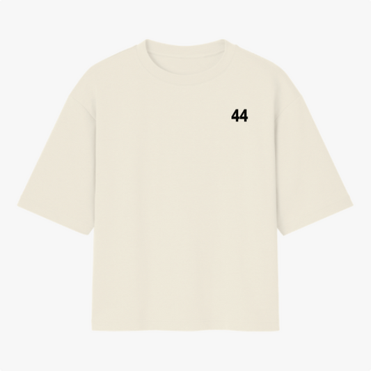 Camiseta com estampa frontal de número "44" pequeno no peito e estampa traseira de piloto segurando bandeira do Brasil, sobreposição de textos.