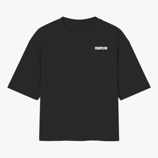 Camiseta com estampa frontal de texto "ESCAPES ME" em letras maiúsculas, localizadas próximo à área do peito esquerdo.