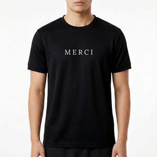 Camiseta com estampa frontal da palavra "MERCI" em letras maiúsculas, com um design simples e sofisticado que destaca a mensagem no centro.