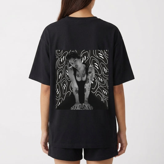 Camiseta com estampa frontal de linha irregular abstrata e estampa traseira de foto de uma pessoa sobre fundo com padrões de linhas fluidas.