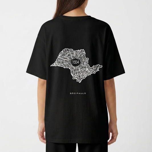 Camiseta com estampa frontal de texto verticalizado "A. SP. PAS" e estampa traseira de mapa estilizado com "1554" no centro, acompanhado de "São Paulo".