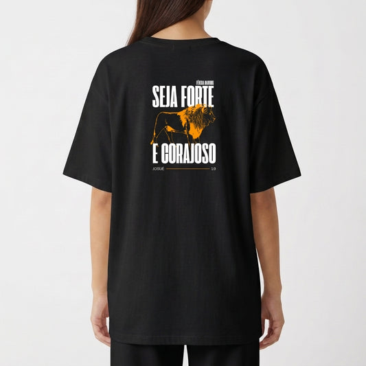 Camiseta com estampa frontal de texto pequeno discreto e estampa traseira de leão imponente com frases encorajadoras acima e abaixo da imagem.