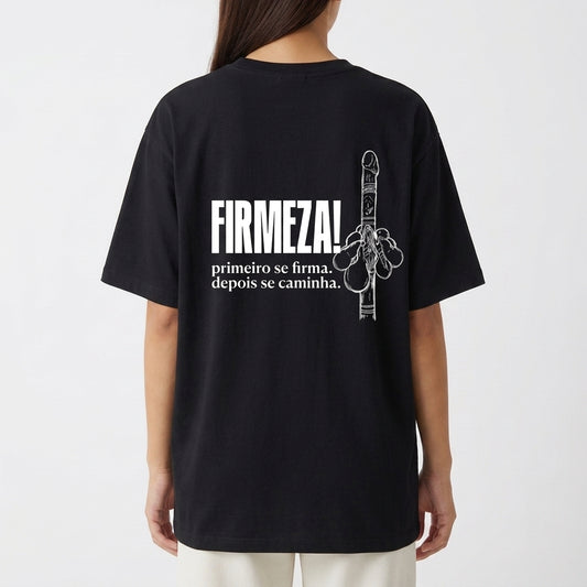 Camiseta com estampa frontal de duas chaves cruzadas detalhadas, e estampa traseira de uma mão levantada ao lado da frase "FIRMEZA! primeiro se firma, depois se caminha.".