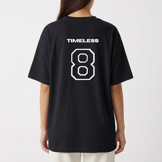 Camiseta com estampa frontal de dois brilhos estilizados e estampa traseira de um número "8" grande, acompanhado da palavra "TIMELESS" acima.