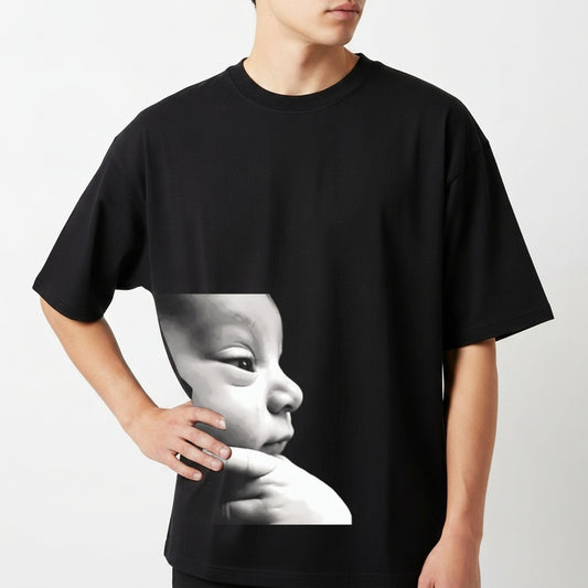 Camiseta com estampa frontal de rosto de bebê em perfil com expressão serena e dedos apoiados no queixo em estilo fotorrealista minimalista.