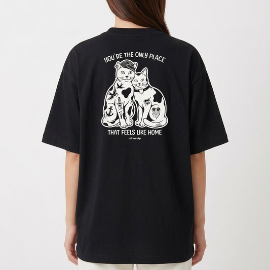 Camiseta com estampa frontal de duas cabeças de gatos em estilo ilustrativo e estampa traseira de dois gatos sentados rodeados por detalhes artísticos.