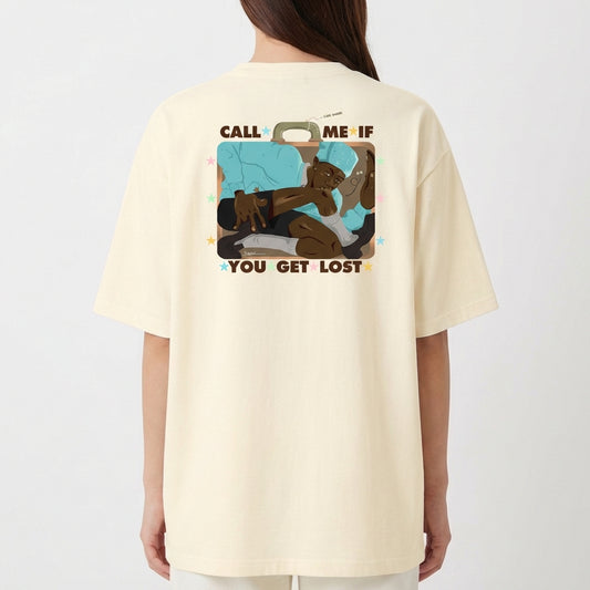 Camiseta com estampa frontal de texto "CALL ME IF YOU GET LOST" adornado com pequenas estrelas coloridas e estampa traseira de ilustração com figura relaxando em mala.