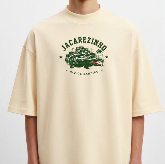 Camiseta com estampa frontal de Jacarezinho, mostrando um crocodilo estilizado com prédios e palmeiras ao fundo, acompanhada das palavras "Rio de Janeiro".