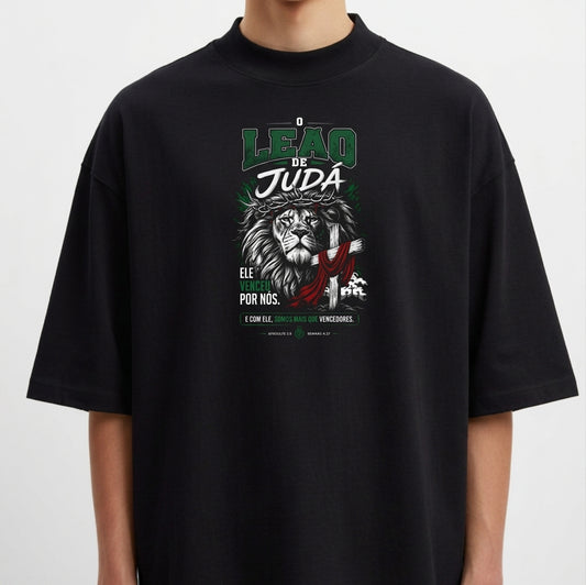 Camiseta com estampa frontal de leão com detalhes gráficos, textos destacando 'Leão de Judá' e frases adicionais em estilo tipográfico.