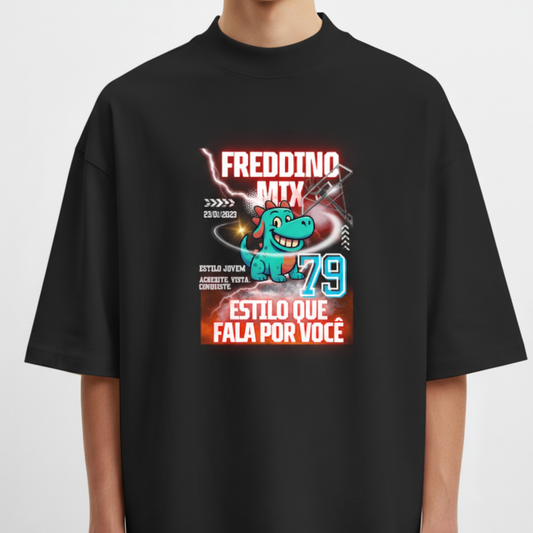 Camiseta com estampa frontal de um dinossauro verde sorridente, acompanhado por textos variados, setas, número "79" e elementos gráficos dinâmicos.