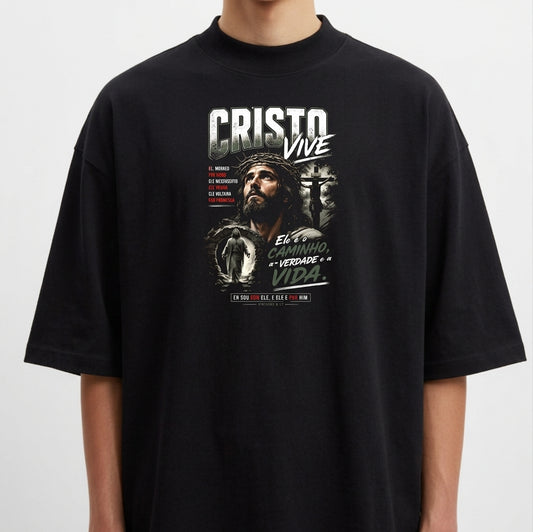 Camiseta com estampa frontal de um rosto cercado por elementos religiosos, incluindo uma cruz, e frases destacando mensagens espirituais.