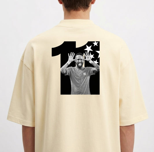 Camiseta com estampa traseira de uma figura dentro do número onze, acompanhada de um fundo repleto de estrelas em um formato dinâmico.