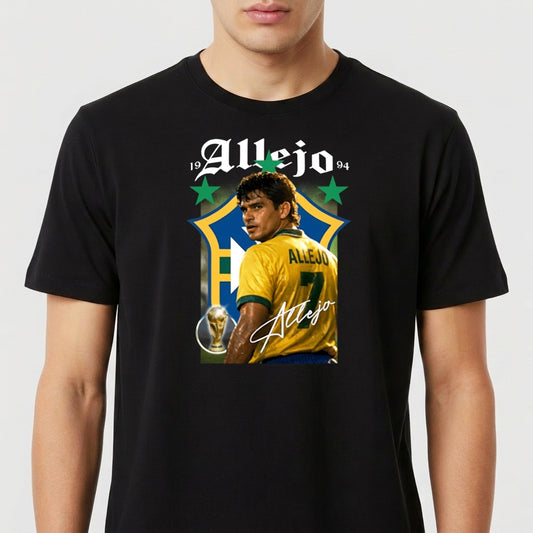 Camiseta com estampa frontal de futebolista com uniforme, troféu e dois anos em destaque acima, em frente a um grande escudo estilizado, assinada em letra cursiva.