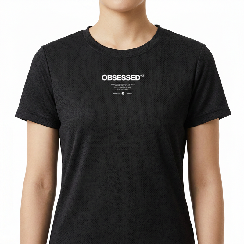 Camiseta com estampa frontal de texto em destaque "OBSESSED" em letras maiúsculas, acompanhada por pequenos detalhes e marcas registradas abaixo.