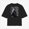 Camiseta com estampa frontal de um logotipo e nome em tamanho pequeno e estampa traseira de um piloto em ação com texto estilizado ao fundo.