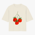 Camiseta com estampa frontal de três tomates brilhantes com hastes verdes, dispostos em um padrão artístico que realça detalhes visuais e cores vibrantes.