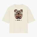Camiseta com estampa frontal de figura com asas e mãos postas em pose de oração, cercada por elementos gráficos e texto em estilo gótico.