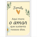 Quadro com estampa de mensagem "Família Aqui mora o amor que sustenta nossos dias" entre ramos de folhas, coração laranja e margarida.