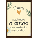 Quadro com estampa de mensagem "Família Aqui mora o amor que sustenta nossos dias" entre ramos de folhas, coração laranja e margarida.