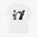 Camiseta com estampa frontal de "RIVALS" em letras discretas e estampa traseira com imagem de dois pilotos se cumprimentando, sobreposta por "RIVALS" repetido.