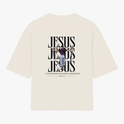 Camiseta com estampa frontal de monograma estilizado e estampa traseira de ilustração de figura crucificada sobreposta a repetição da palavra "JESUS".