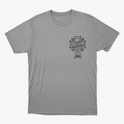 Camiseta com estampa frontal de cruz contendo a frase "Lugar abençoado" e símbolo decorativo, e estampa traseira de texto "LAB" em destaque.