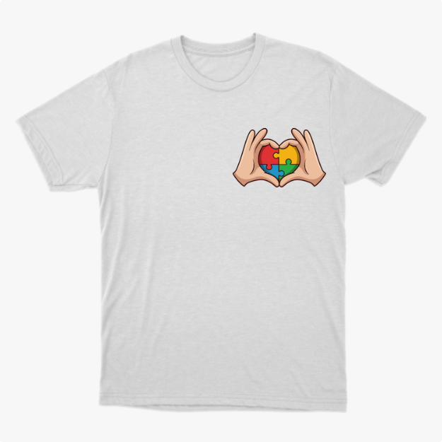 Camiseta com estampa frontal de mãos formando coração com peças de quebra-cabeça coloridas e estampa traseira com frase sobre autismo em diferentes cores.