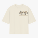 Camiseta com estampa frontal de design intrincado com elementos florais ao redor de texto e estampa traseira de figura mística centralizada com ornamentos detalhados.