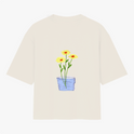 Camiseta com estampa frontal de texto em letras simples "Il raccolto è inevitabile." e estampa traseira de vaso azul com três flores amarelas e caule verde.