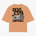 Camiseta com estampa frontal de logo pequeno escrito “VIGIA” no centro e estampa traseira de controle de videogame com frase “DEUS ESTÁ NO CONTROLE”.