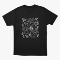 Camiseta com estampa frontal de desenhos sorridentes de criaturas vegetais estilizadas, cercadas por delicados detalhes de flores e folhagens diversas.