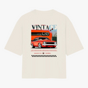 Camiseta com estampa traseira de carro vintage estilizado, com destaque para faróis e grade frontal, acompanhada da palavra "VINTAGE" e padrão quadriculado.
