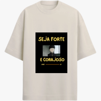 Camiseta com estampa frontal de personagem de cabelo curto em estilo desenho animado com mensagem inspiradora "SEJA FORTE E CORAJOSO" em letras destacadas.