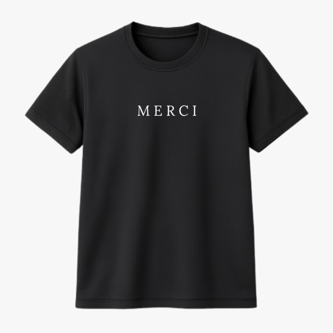 Camiseta com estampa frontal da palavra "MERCI" em letras maiúsculas, com um design simples e sofisticado que destaca a mensagem no centro.