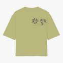 Camiseta com estampa frontal de design intrincado com elementos florais ao redor de texto e estampa traseira de figura mística centralizada com ornamentos detalhados.