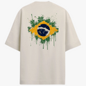 Camiseta com estampa frontal de pequeno emblema circular estilizado no canto superior e estampa traseira de bandeira do Brasil em efeito de respingos de tinta.