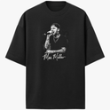 Camiseta com estampa frontal de um artista cantando no microfone, vestindo boné e camisa preta, destacando tatuagens nos braços e autógrafo abaixo.