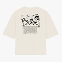 Camiseta com estampa frontal da palavra "brave" em letras estilizadas e efeito de brilho, e estampa traseira de texto "be brave" com desenho de leão.