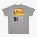 Camiseta com estampa frontal de guerreiro musculoso segurando uma arma sobre fundo circular e estampa traseira de personagem em pose poderosa com texto.