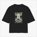 Camiseta com estampa frontal de texto estilizado "OS" e estampa traseira de cruz sobre ondas turbulentas, nuvens dramáticas e a frase "IN THE STORM HE REMAINS".