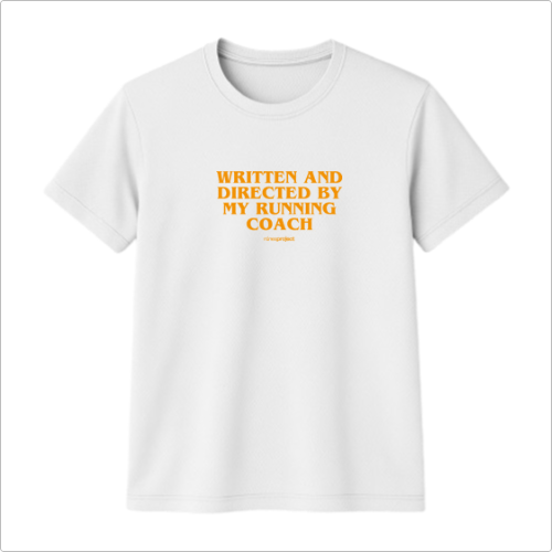 Camiseta com estampa frontal de texto que diz "WRITTEN AND DIRECTED BY MY RUNNING COACH" acompanhado de um pequeno logo ou assinatura abaixo.