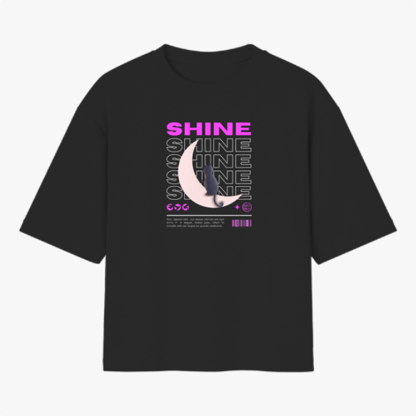 Camiseta com estampa frontal de texto "SHINE" repetido em camadas, sobreposto a uma meia-lua detalhada e pequena figura de um gato.