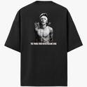 Camiseta com estampa frontal de assinatura estilizada e estampa traseira de retrato de homem sem camisa, assinaturas e frase "The Prince Who Never Became King".
