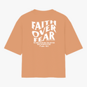 Camiseta com estampa frontal de "Faith Over Fear" com detalhes em texto pequeno e estampa traseira de "Faith Over Fear" acompanhada de citação extensa.