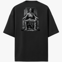 Camiseta com estampa frontal de logotipo estilizado com ornamentos e estampa traseira de figura esquelética sentada em um trono com detalhes rústicos.
