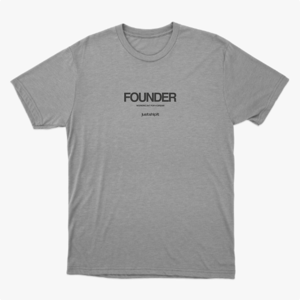 Camiseta com estampa frontal de texto "FOUNDER" em destaque, acompanhada pela frase "WORKING 24/7 FOR A DREAM" e logotipo "justshipit" abaixo.