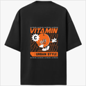 Moletom com estampa traseira de personagem laranja estilizado segurando uma flor, rodeado por repetição da palavra "VITAMIN" e texto "URBAN STYLE".
