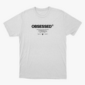 Camiseta com estampa frontal de texto grande "OBSESSED" seguido por linhas menores que incluem mensagens inspiradoras e dois logotipos pequenos abaixo.