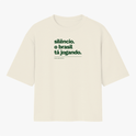 Camiseta com estampa frontal de texto "silêncio. o brasil tá jogando." com assinatura "FALAR, NÃO MURMURAR." e estampa traseira de "VERDELO" no topo.